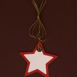 Red star-shaped ornament with golden string on a dark backdrop, perfect for holiday decoration.